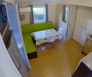 Coin repas avec banquette et kitchenette dans le mobil home Les Salins de la Gardiole