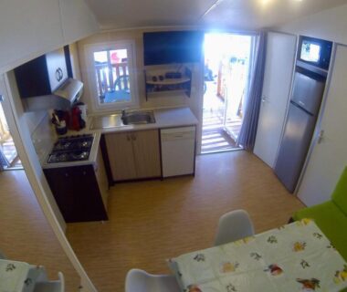 Intérieur de mobil-home avec kitchenette et coin repas au camping Les Salins de la Gardiole