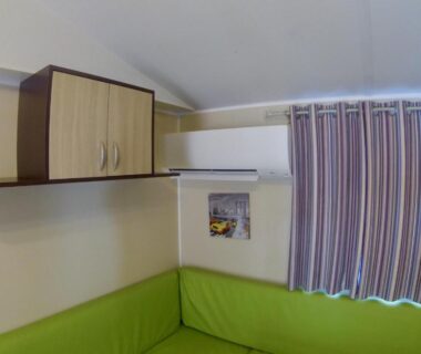 Coin salon avec banquette verte et meuble haut dans le logement Les Salins de la Gardiole