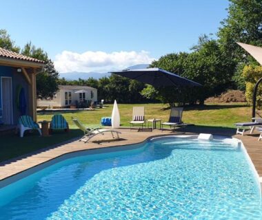 Piscine extérieure avec transats parasols et abri près de la pelouse au camping Les chalets Salinéens