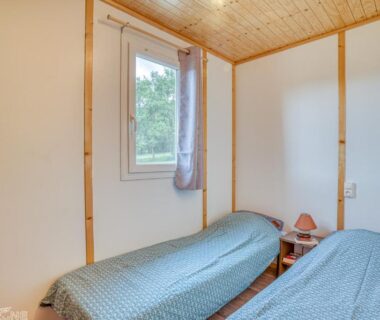 Chambre avec deux lits et fenêtre au camping Les chalets de Dordogne