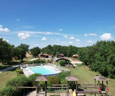 Piscine extérieure avec chalets autour au camping Les chalets de Dordogne