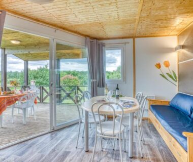 Salon avec table et terrasse ouverte sur la campagne dans Les chalets de Dordogne
