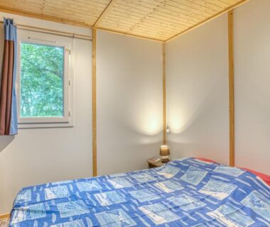 Chambre avec lit double fenêtre et lampe dans Les chalets de Dordogne