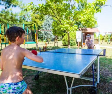 Espace extérieur avec table de ping pong et enfants au camping Les chalets de fiolles