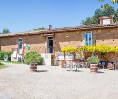Façade et terrasse avec tables et tonneaux à l'établissement Les chalets de fiolles