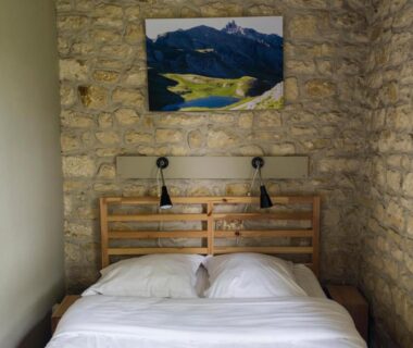 Chambre avec lit double et mur en pierre dans Les gites de Sarlat