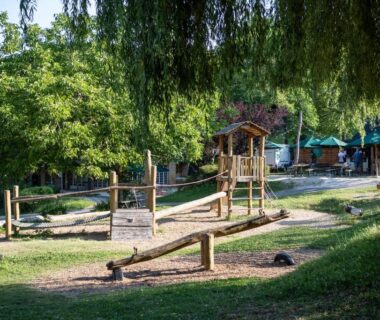 Aire de jeux en herbe sous arbres au camping Les gites de Sarlat