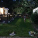 Pelouse éclairée entre mobil-homes la nuit dans Les mobil homes d’oliver rob