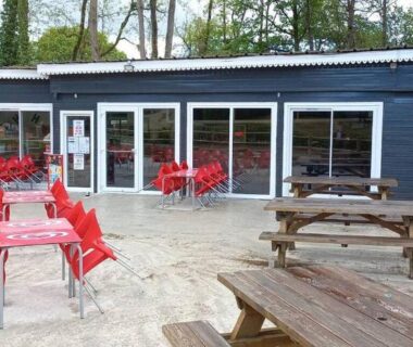 Terrasse extérieure avec tables et chaises rouges au camping Les mobil homes d’oliver rob