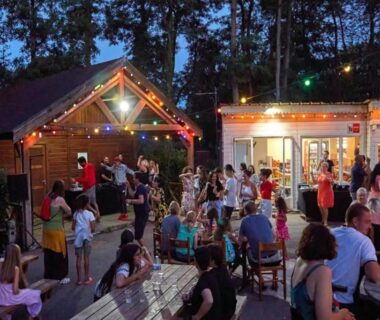 Terrasse extérieure animée avec guirlandes lumineuses et convives au camping Les mobil homes d'oliver rob