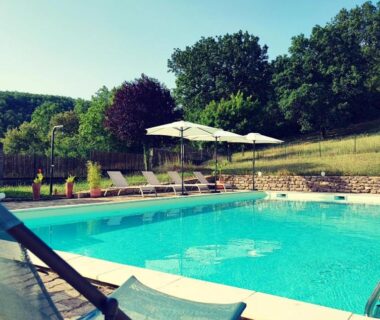 Piscine extérieure avec transats et parasols au camping Les nids de Bonnan