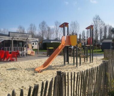 Aire de jeux sablée avec toboggan et palissade dans le camping Les pieds dans l'Orne