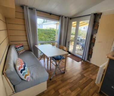 Salon avec banquette et table donnant sur la terrasse du mobil home Les pieds dans l'Orne