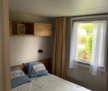 Chambre avec lit double et fenêtre dans le camping Les pieds dans l'eau, le coeur en vacances