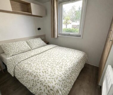 Chambre avec lit double et fenêtre donnant sur extérieur au camping Les sables chal’heureux