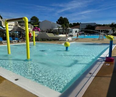 Piscine extérieure avec pataugeoire et parasols au camping Les sables chal’heureux
