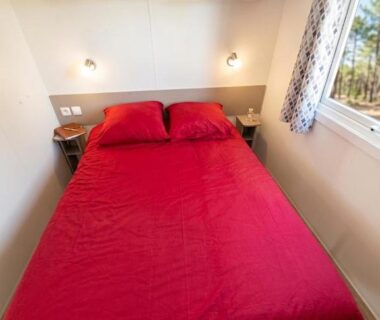 Chambre avec lit double et fenêtre donnant sur l'extérieur au camping Les sables du midi