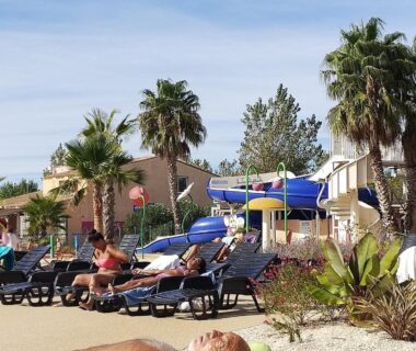 Bord de piscine avec transats et toboggans au camping Les sables du midi
