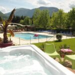 Piscine extérieure et jacuzzi face aux montagnes au camping L'imprévu