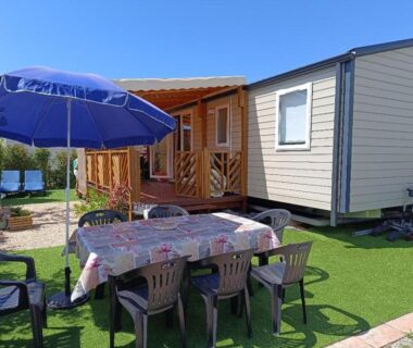 Terrasse avec table plastique et parasol du mobil-home L'incontournable Tout Confort Camping Siblu