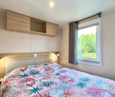 Chambre avec lit double et fenêtre donnant sur le jardin du L'incontournable Tout Confort Camping Siblu