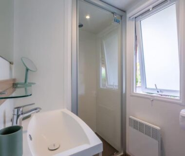 Salle de bain avec cabine de douche lavabo et fenêtre dans le camping Little John