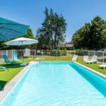 Piscine extérieure avec parasols et transats au Lodge 2 Domaine Des Landes