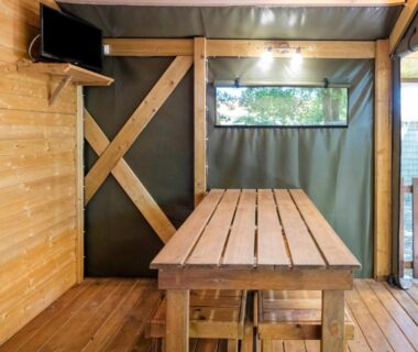 Terrasse couverte avec table en bois et télévision du Lodge 2 Domaine Des Landes