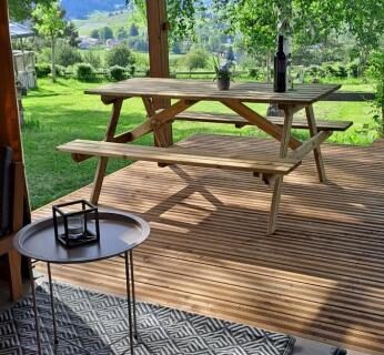Terrasse couverte avec table en bois, bouteille et vue sur les arbres dans le Lodge Safari tent
