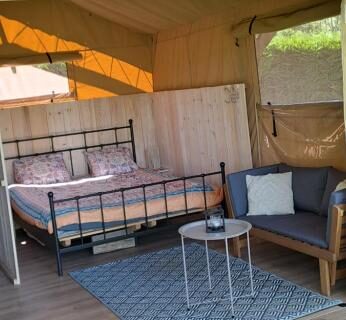 Terrasse en bois avec lit et coin salon dans le Lodge Safari tent
