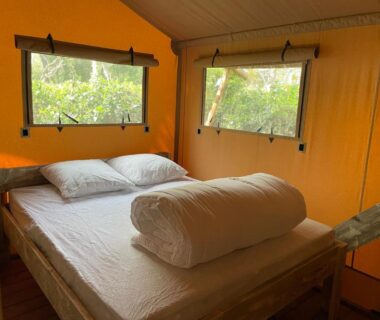 Intérieur de tente lodge avec lit double et fenêtres donnant sur la végétation dans le Lodges & Nature - 49