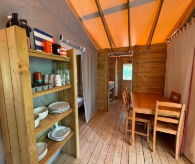 Intérieur de lodge avec étagère vaisselle et coin repas dans les Lodges du Bois Dodo