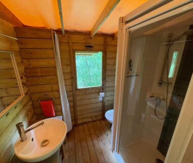 Salle de bains en bois avec douche et lavabo dans les Lodges du Bois Dodo