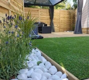 Terrasse avec gazon synthétique et galets blancs au Logement calme