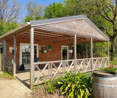 Terrasse couverte en bois devant un bâtiment au camping L'orée du bois
