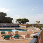 Terrasse au bord de la piscine avec transats du camping Lou Soleil 80