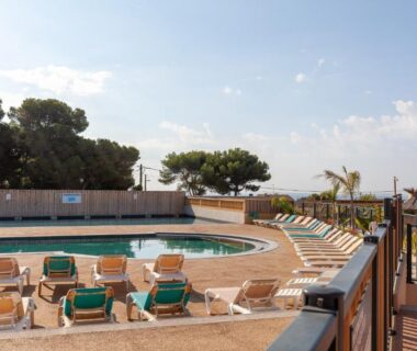 Terrasse au bord de la piscine avec transats du camping Lou Soleil 80