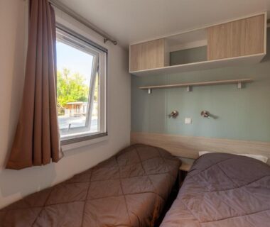 Chambre avec deux lits et fenêtre dans le logement Lou Soleil 80