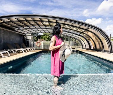 Piscine couverte au bord de laquelle se tient une femme en robe rose au Lov'nid spa et sauna