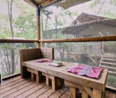 Terrasse couverte avec banquette et table dressée au Ludocamping