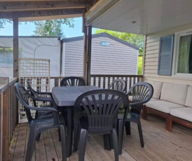 Terrasse couverte avec table, chaises et banquette du mobil-home Lya