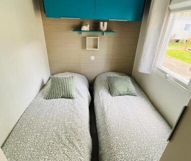 Chambre avec deux lits simples et fenêtre dans le MH 142B du camping Les dunes de Contis