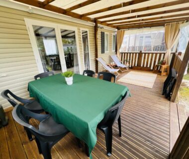 Terrasse couverte avec table verte et transats du MH 142B Camping Les dunes de Contis