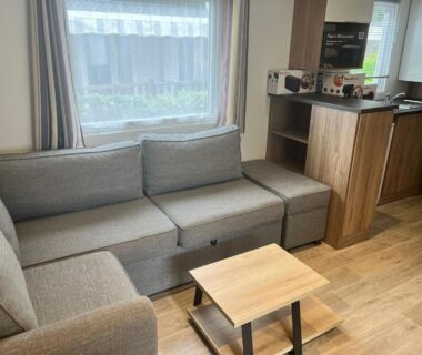 Coin salon avec canapé et kitchenette dans le MH 305 3 chambres et 1 salle de bain dan camping 4