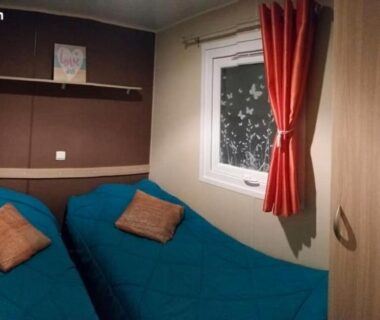Chambre avec deux lits fenêtre et armoire du MH 387 3 chambres 1 salle de bain dans camping 4 étoiles