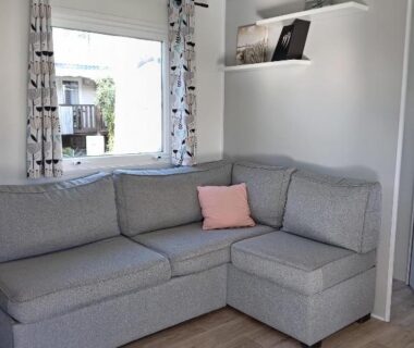 Salon avec canapé d'angle gris et coussin rose dans le MH 495 SALSA 2 chambres et 1 salle de bain
