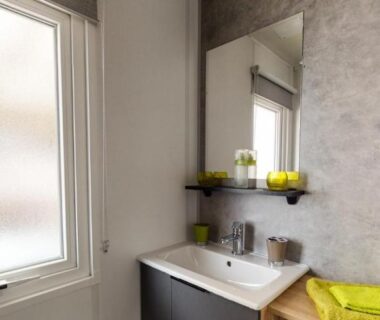 Salle de bain avec lavabo miroir fenêtre serviette verte dans le MH 6-8p tt équipé camping 4e bord de lac