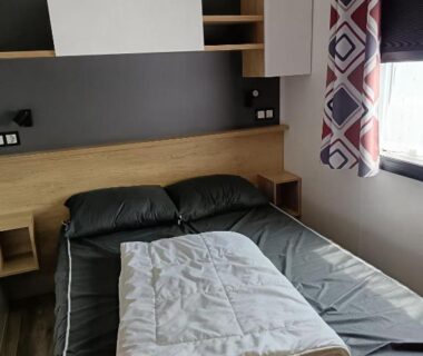 Chambre avec lit double et couette pliée dans le MH 805 Camping Bois Dormant