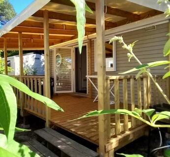 Terrasse en bois ombragée par des pins au mobil-home MH Bx